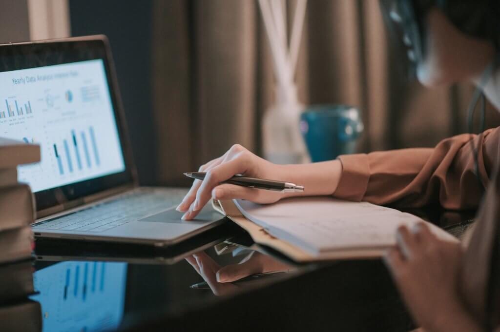 woman using laptop working from home in study room writing headset