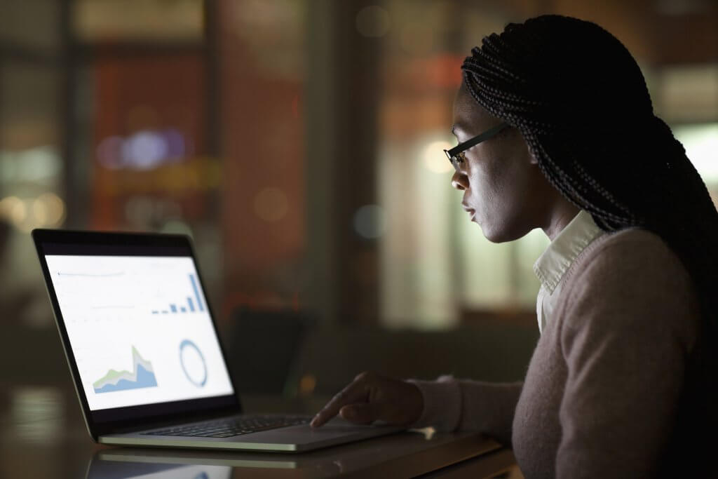 Woman viewing laptop screen at night, demostrating good data journalism skills as she's creating and/or analyzing data visualizations.