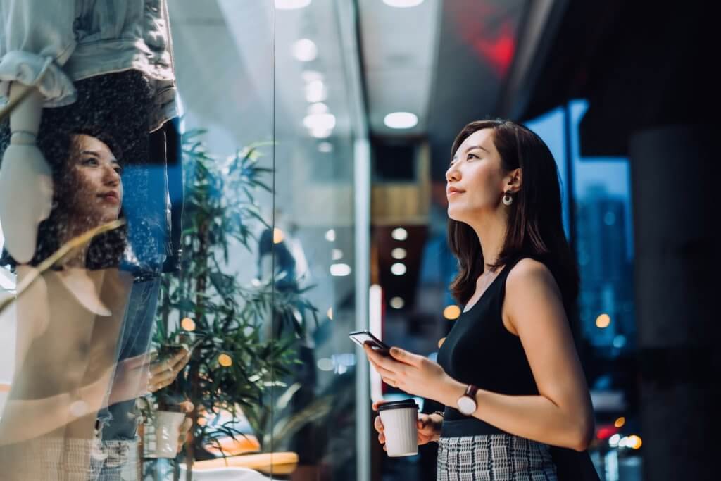girl looking into shop windoe before making purchase