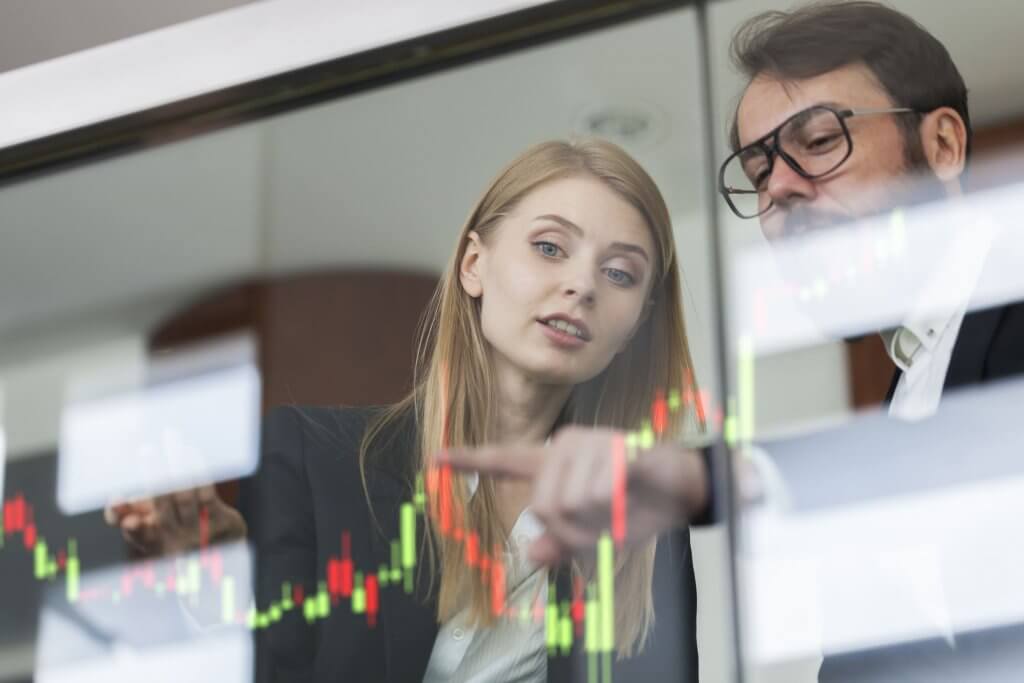 man and woman looking at a chart on glass screen